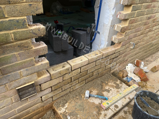 Brick wall construction with tools and materials scattered on the ground.