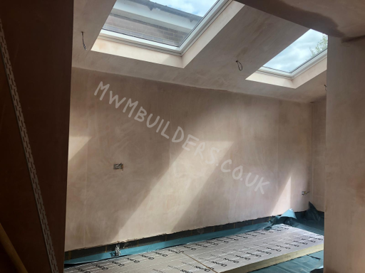 Empty room with skylights and unfinished plastered walls, featuring a floor with underfloor heating.