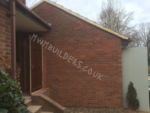 Brick wall of a building with a wooden door and a website name painted on it.