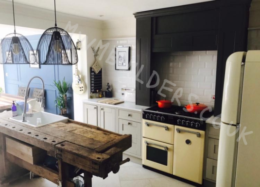 Modern kitchen with a rustic wooden island, white cabinets, and appliances.