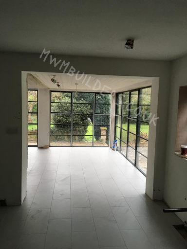 A spacious interior room with large glass doors leading to a garden.