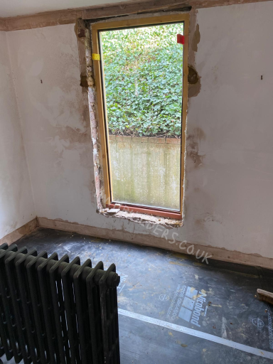 View of an unfinished room with a window, exposed walls, and a radiator.