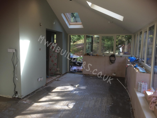 Open interior space with large windows, skylights, and unfinished walls and floor.