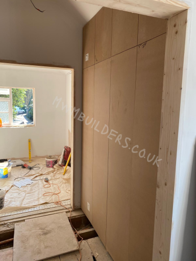 Interior view of a room under construction, featuring unfinished walls and scattered tools.