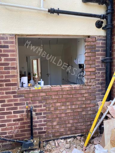 Window opening in a brick wall, revealing an interior space under construction.