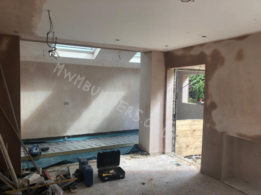 Empty room under renovation with unfinished walls and construction tools visible.